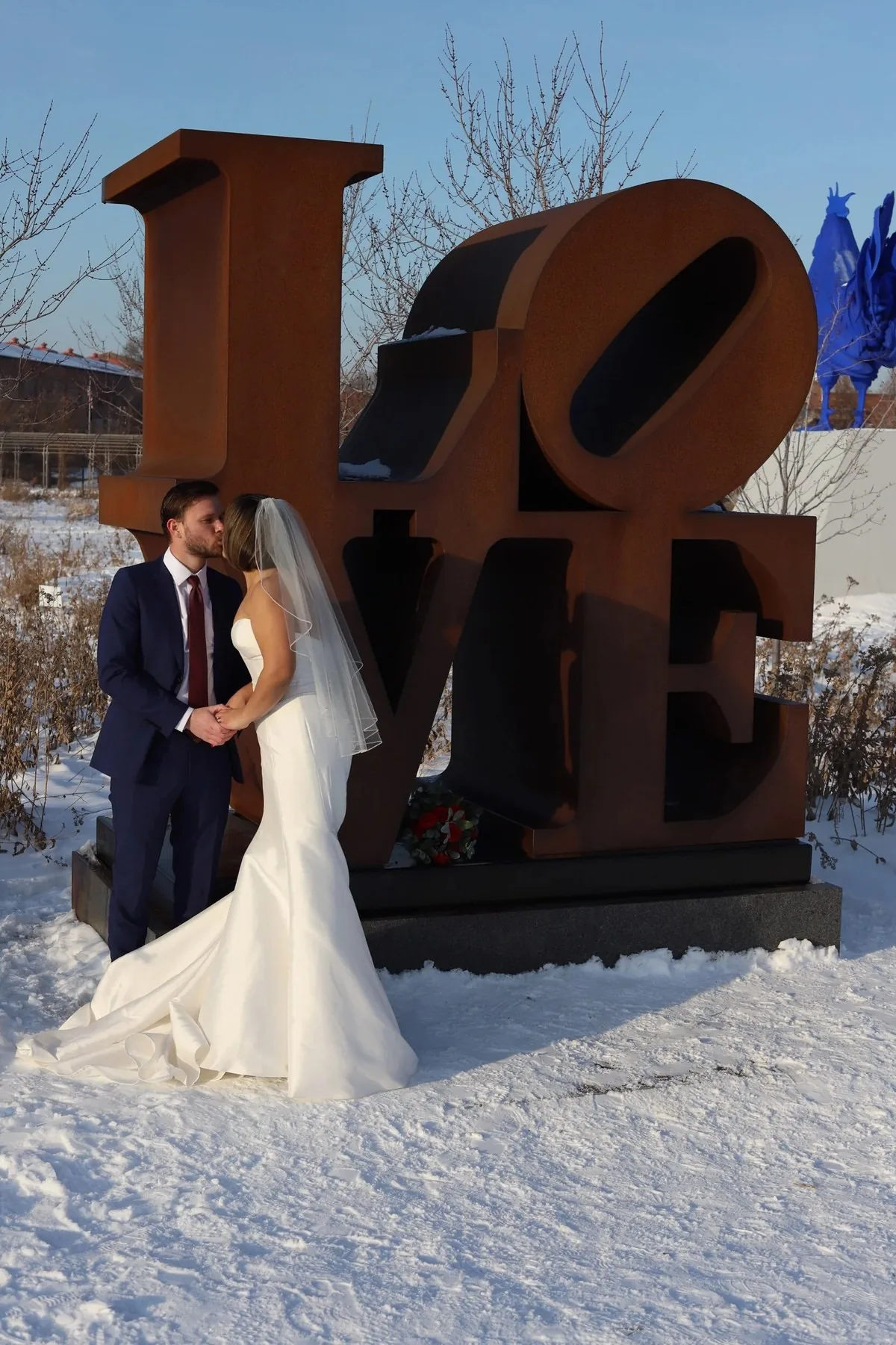 Bride and groom posing beside a LOVE sculpture
