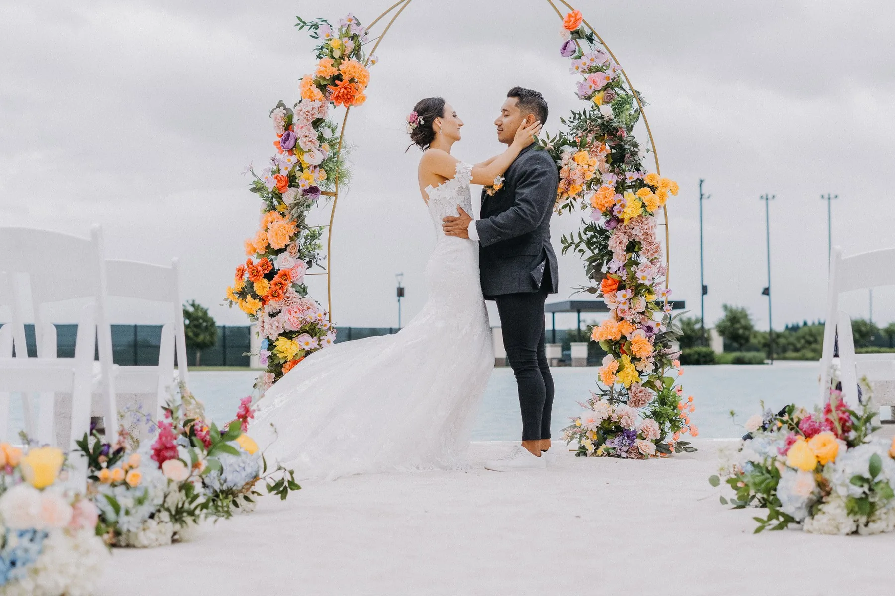 Modern Affinity couple celebrating in front of a vibrant floral ceremony arch
