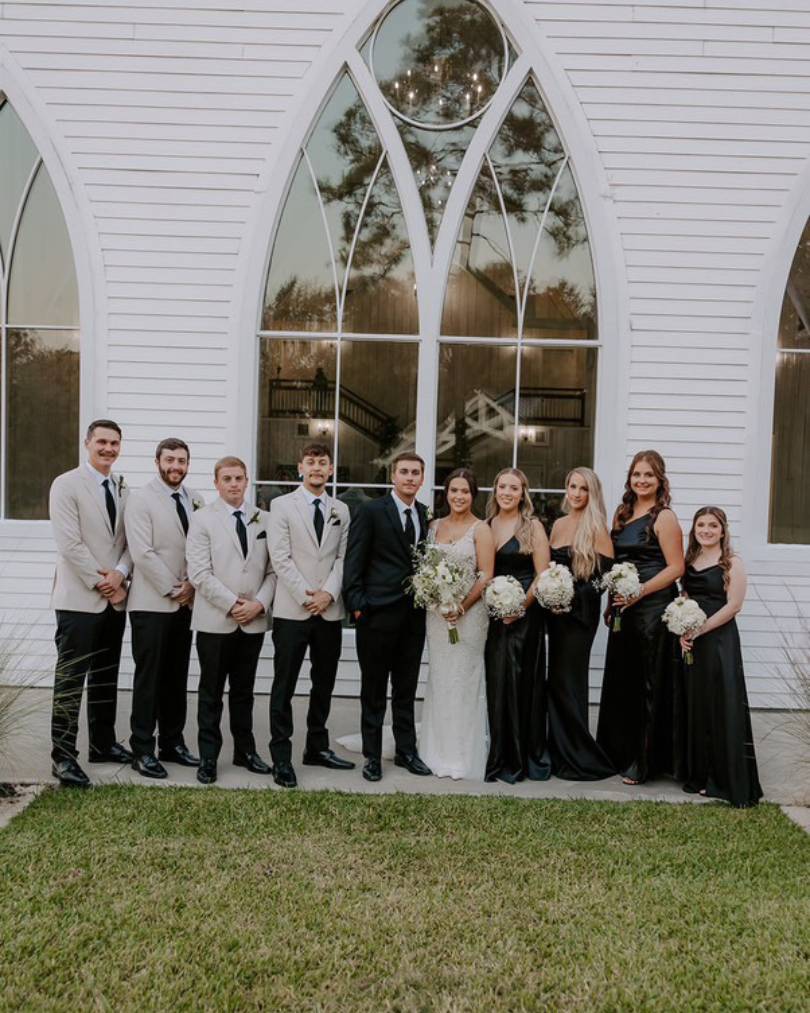 bride and groom with wedding party in grey suits and black dresses while the bride is in Evelyn, a justin alexander gown.