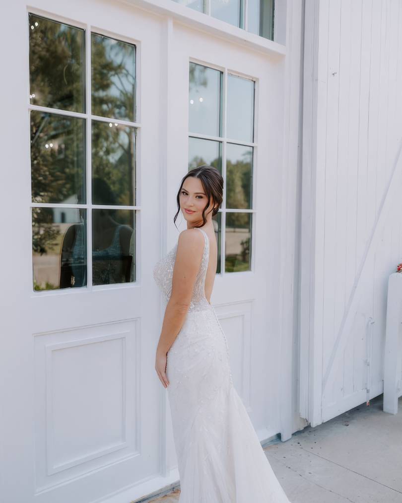 bride looking over her shoulder, walking towards the reception hall at the springs wallisville event venue. 