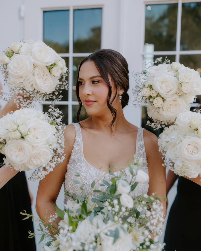 bride looking to the right in evelyn, a justin alexander wedding dress, surrounded by bridesmaid bouquets