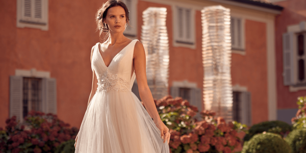 Model wearing a randy fenoli wedding gown with background swirls behind heavenly collection trunk show