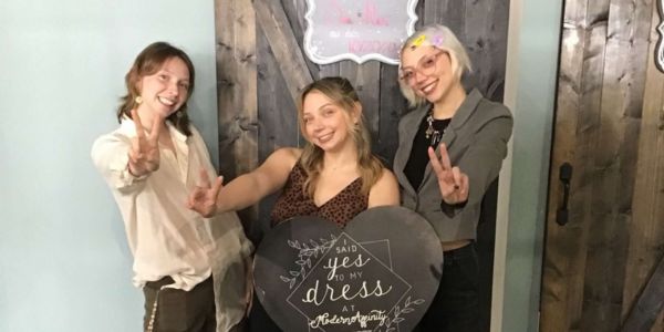 engaged bride with her family sending peace signs in front of Modern Affinity bridal suite