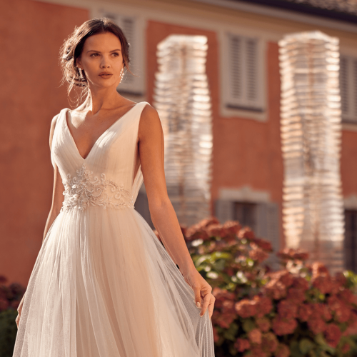 Model wearing a randy fenoli wedding gown with background swirls behind heavenly collection trunk show